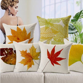 Cream cushion covers with colourful autumn leaf prints arranged on a sofa.