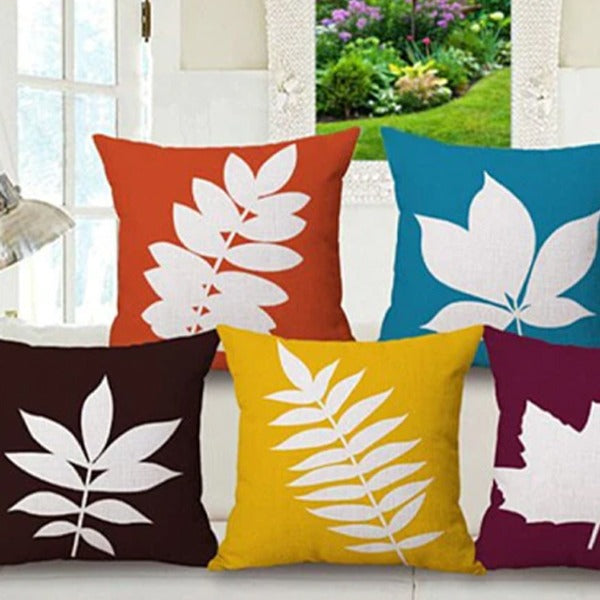 Five brightly coloured cushion covers with bold white leaf silhouettes.