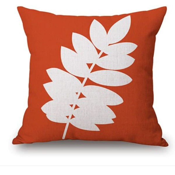 Orange cushion cover with a white leafy branch.
