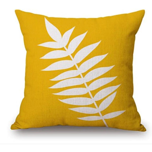 Mustard cushion cover with a large white fern-like leaf.