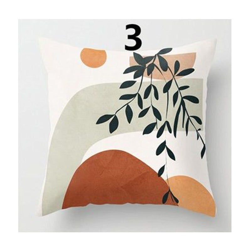 Cream cushion cover with black leaves and overlapping rust, peach and pale green shapes.