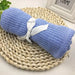 Rolled blue cellular blanket tied with a white ribbon on a woven mat.