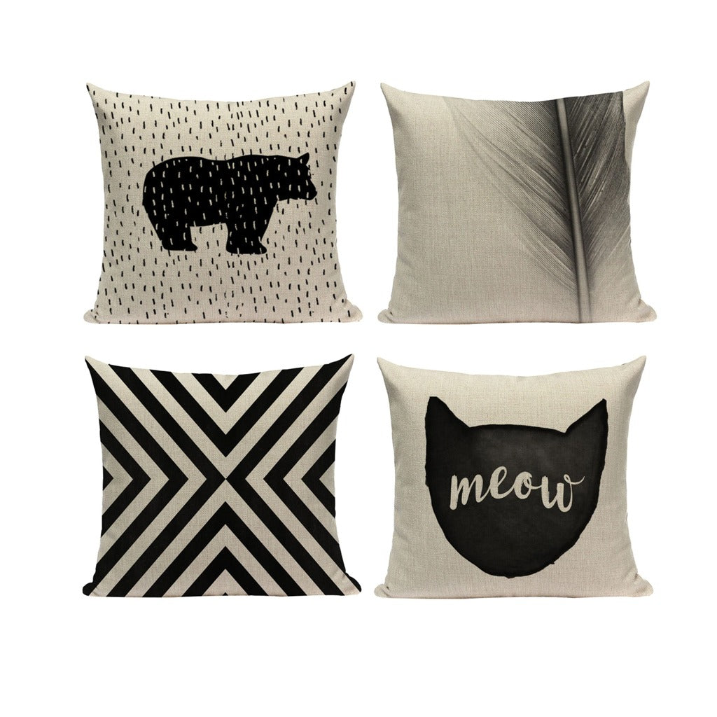 Four cream and black cushion covers with bear, cat, stripe and leaf designs.