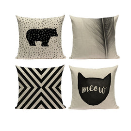 Four cream and black cushion covers with bear, cat, stripe and leaf designs.