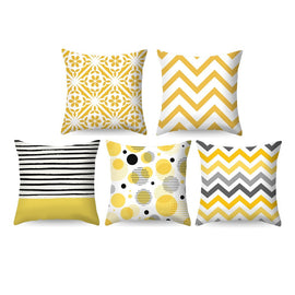 Five yellow, black and white cushion covers with floral, striped and geometric patterns.