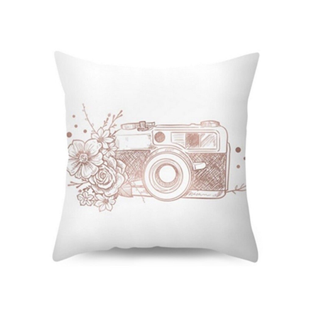 White cushion cover with a rose-toned camera and floral illustration.