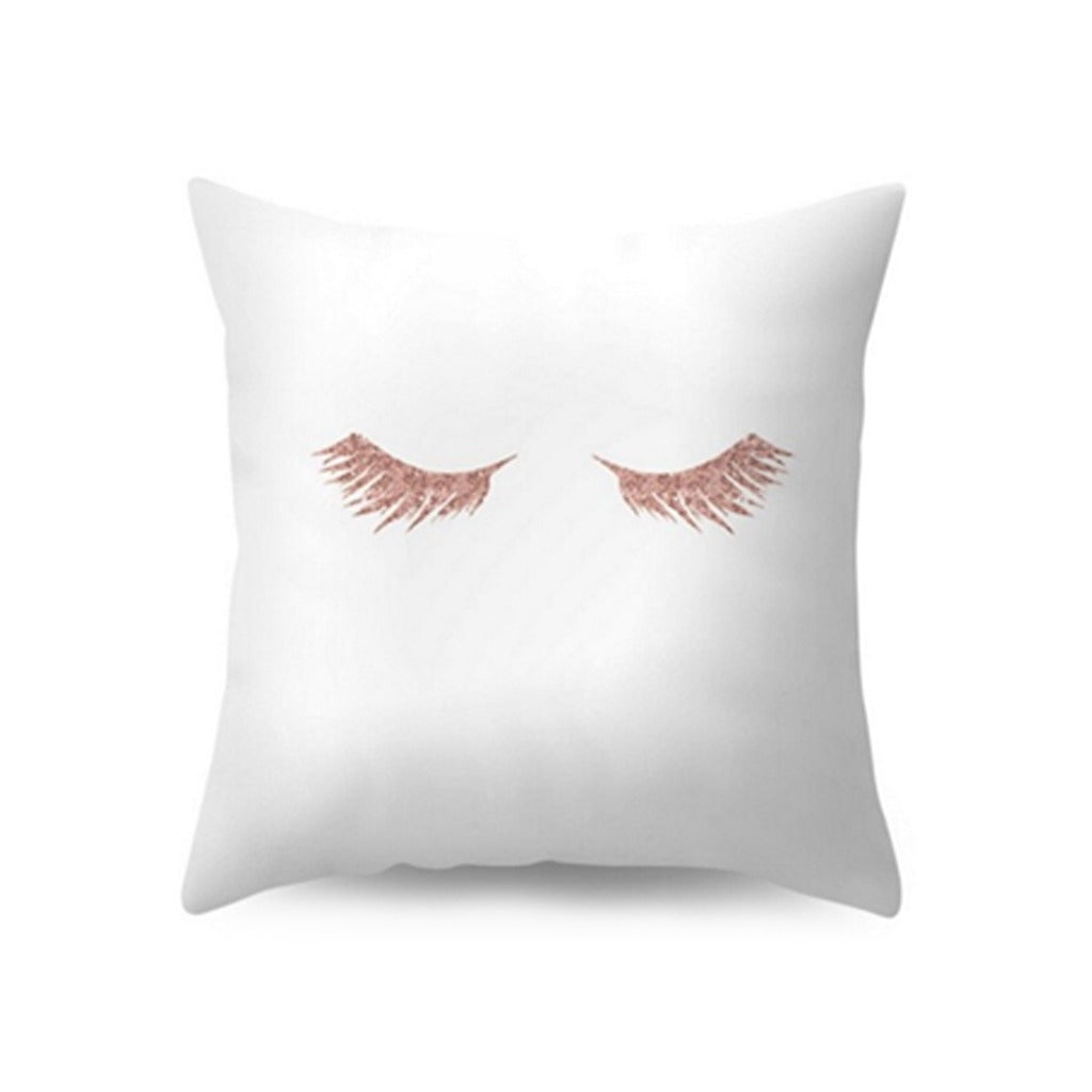 White cushion cover with a rose-toned eyelash illustration.