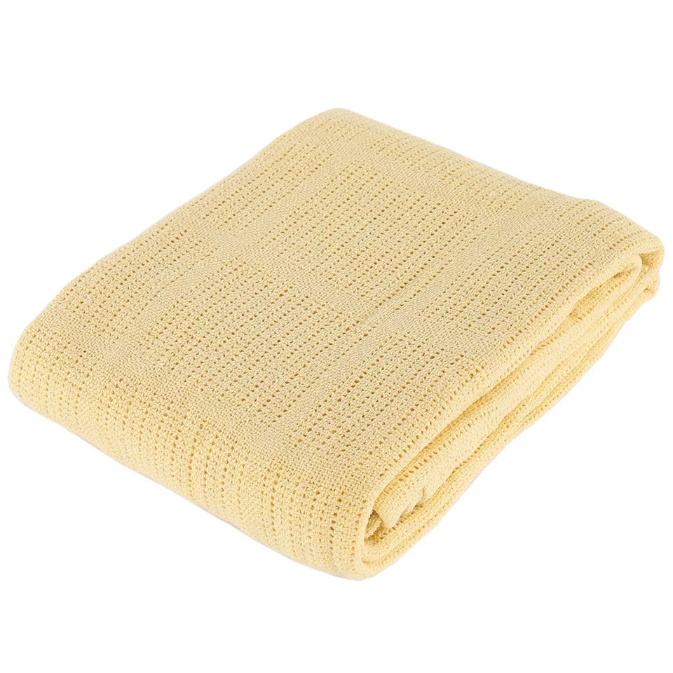 Folded pale yellow textured blanket on a white background.