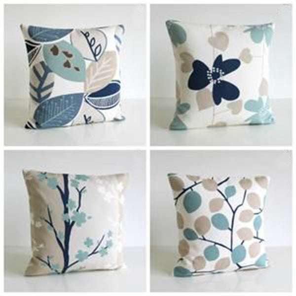 Four cushion covers with muted blue and green leaves, flowers and branches.