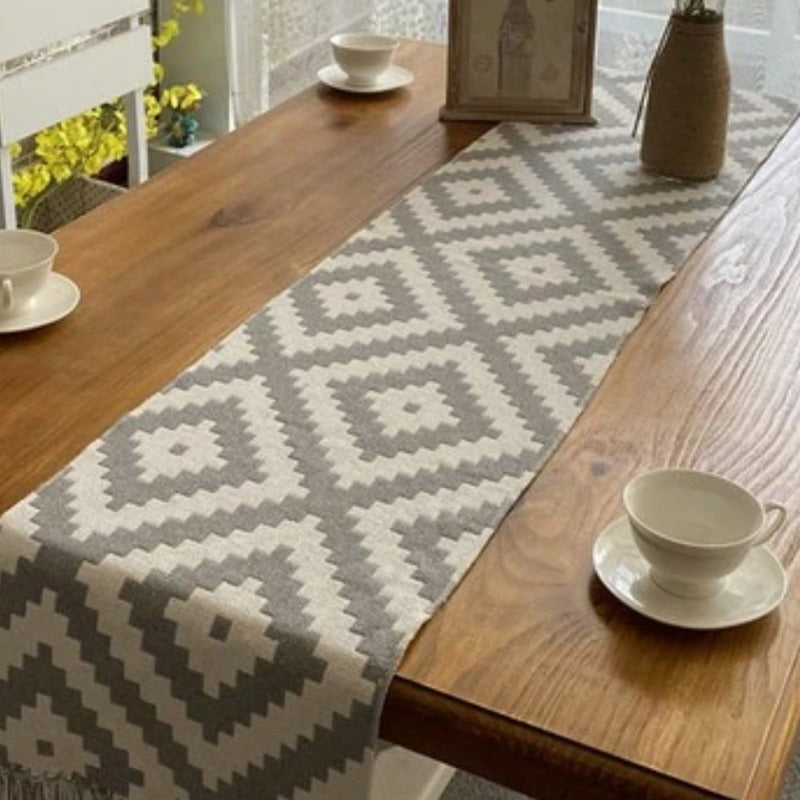 Grey and white diamond-pattern table runner on a wooden table.