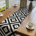 Black and white diamond-pattern table runner on a wooden table.