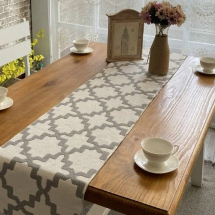 Grey and white trellis-pattern table runner on a wooden dining table.