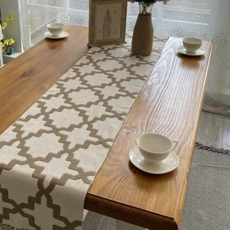 Grey and white trellis-pattern table runner on a wooden dining table.