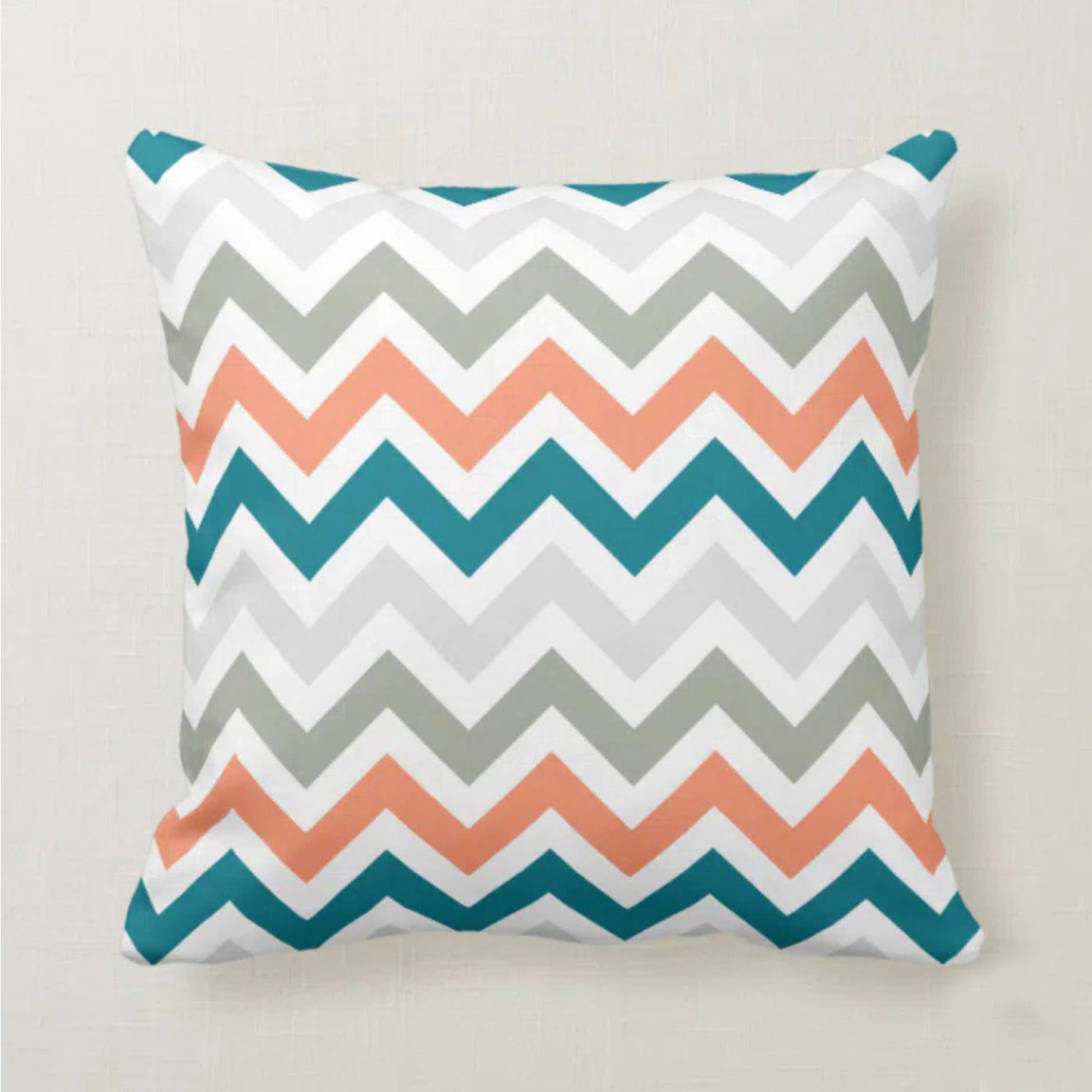 Cushion cover with coral, teal, grey and white chevrons.