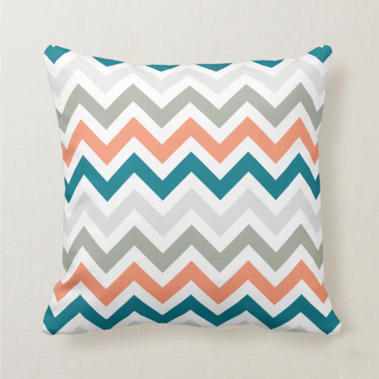 Cushion cover with coral, teal, grey and white chevrons.