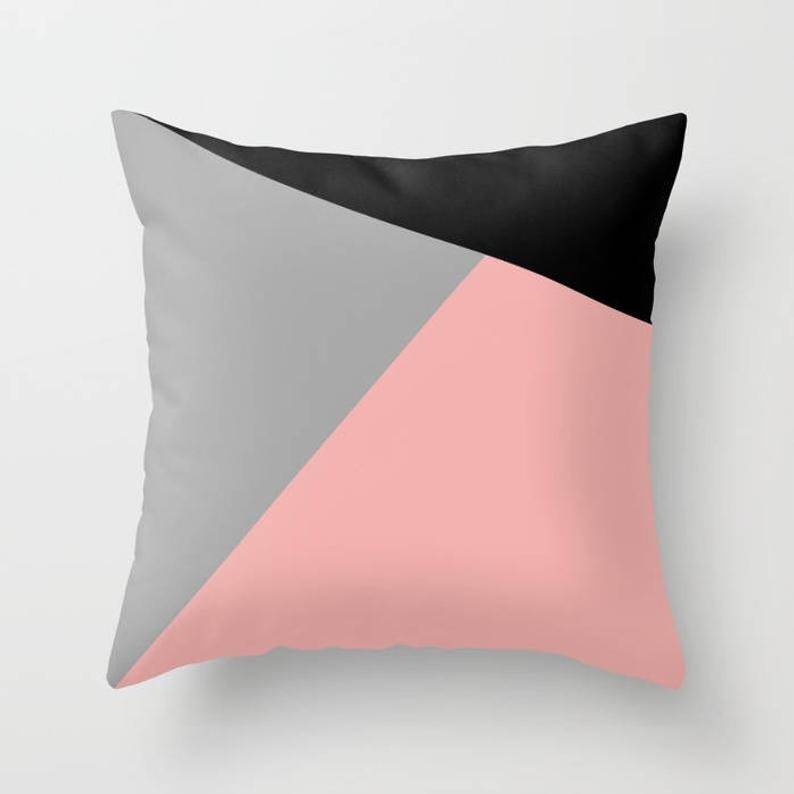 Cushion cover with blush pink, grey and black geometric panels.