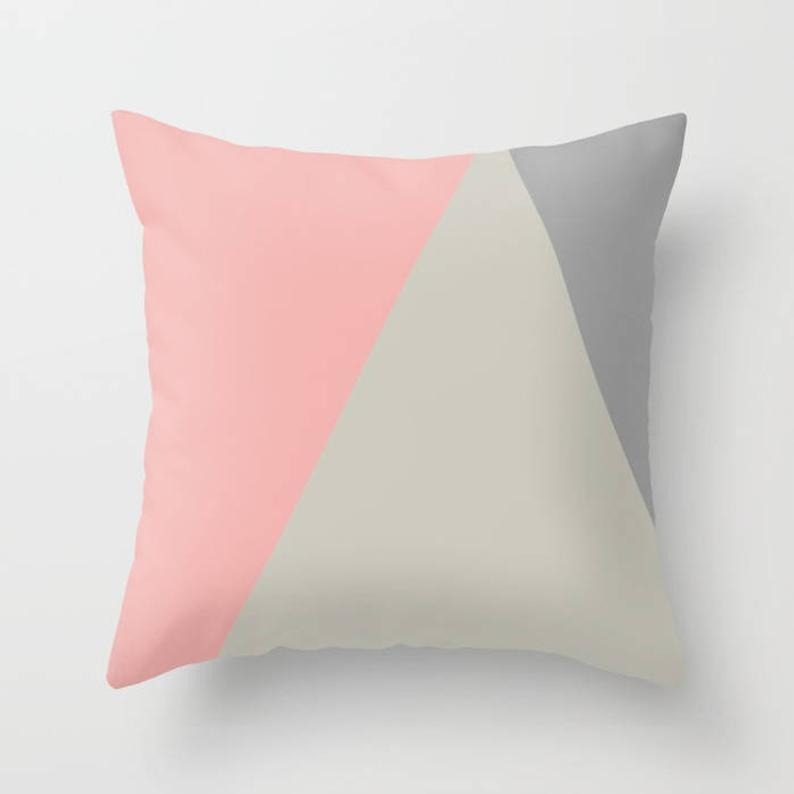 Cushion cover with blush pink, cream and light grey geometric panels.