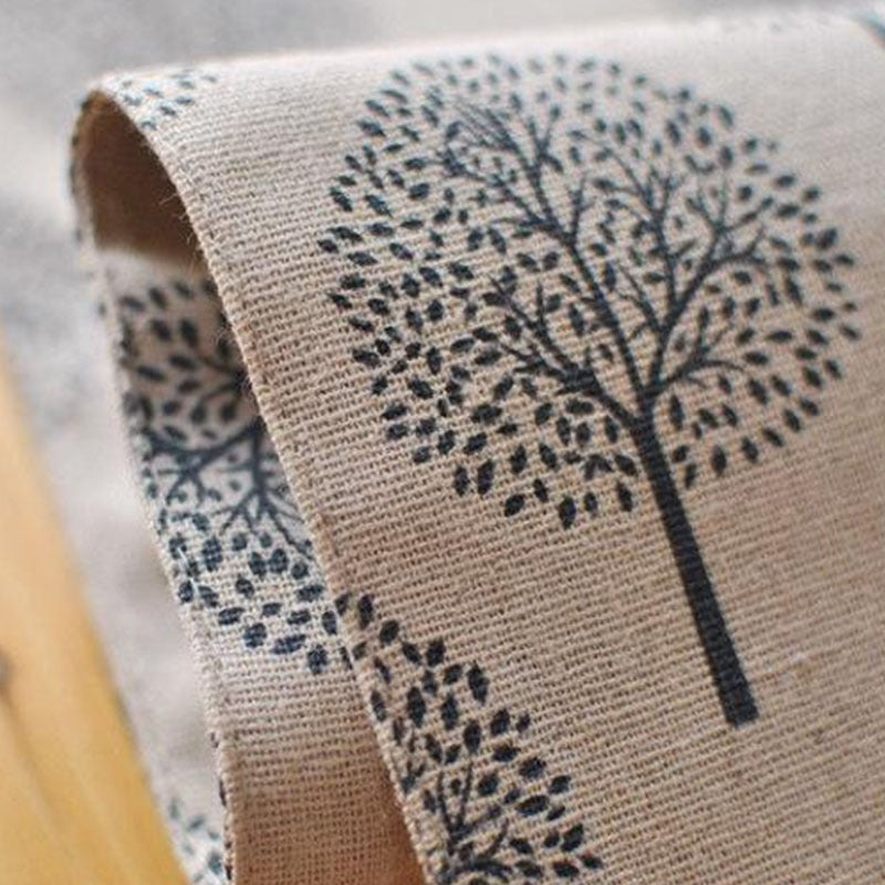 Close-up of the edge and tree print on a beige table runner.