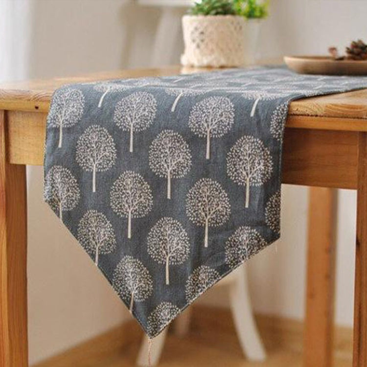 Grey tree-pattern table runner draped over a wooden table.
