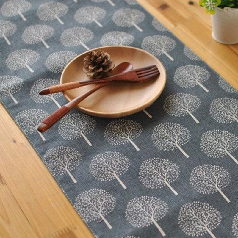 Grey tree-pattern table runner shown beneath a plate and cutlery.