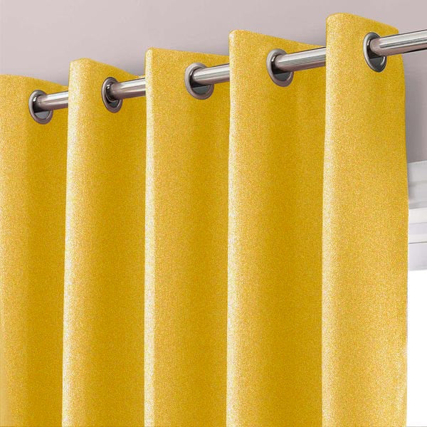 Close-up of gold curtain fabric and metal eyelets on a curtain rod.
