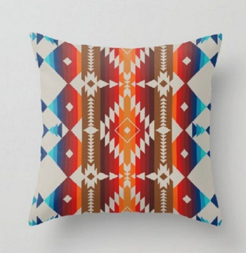 Cushion cover with red, cream and blue geometric striped motifs.