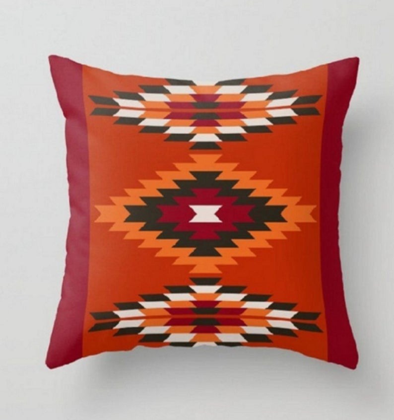 Terracotta cushion cover with black, cream and yellow geometric diamond motifs.