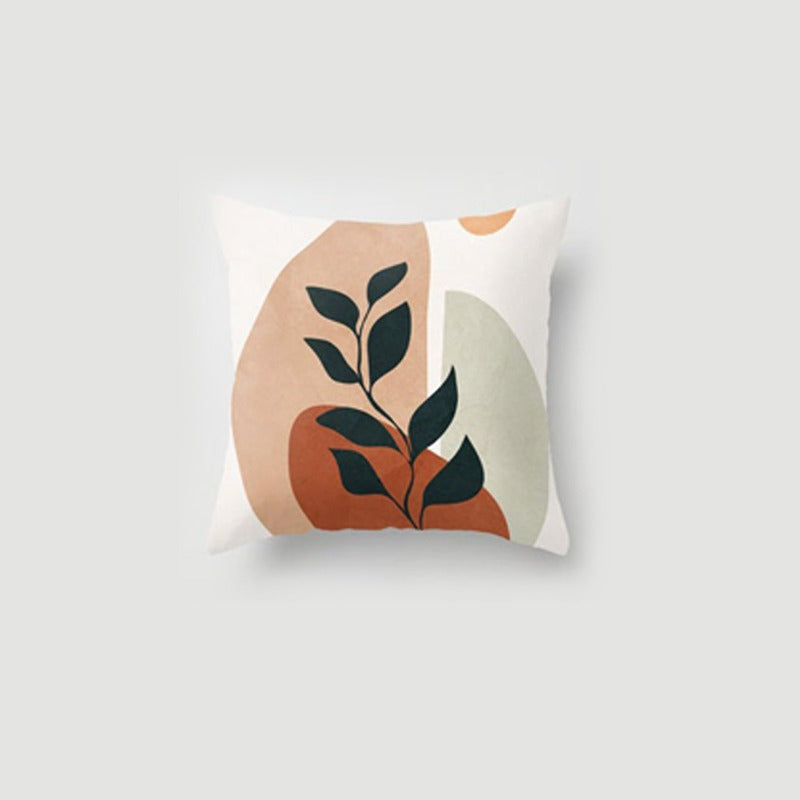 Cushion cover with black leaves over warm peach and cream abstract shapes.