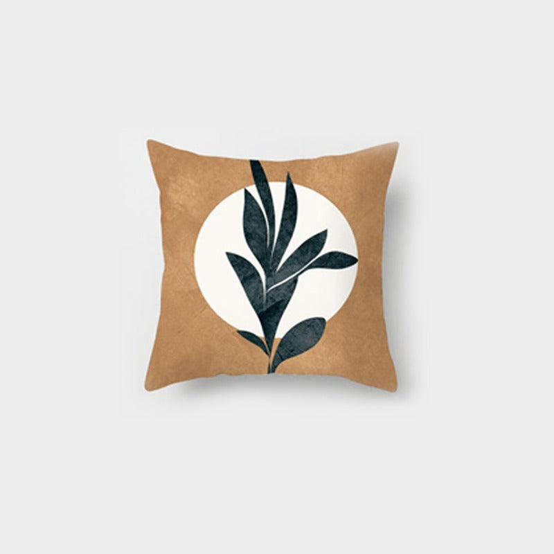 Tan cushion cover with a dark leafy sprig over a cream shape.