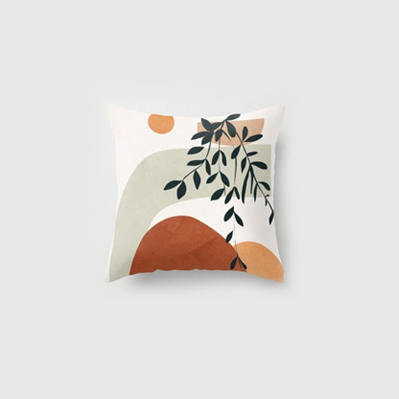 Cream cushion cover with a leafy branch and a rust-coloured semicircle.