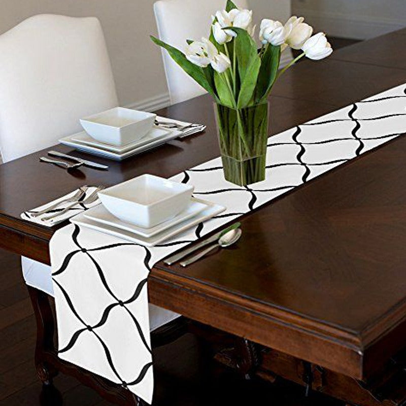 White table runner with black curved trellis lines on a dark dining table.
