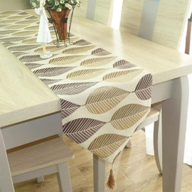 Beige and grey leaf-pattern table runner with a tasselled end.
