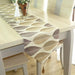 Beige and grey leaf-pattern table runner with a tasselled end.