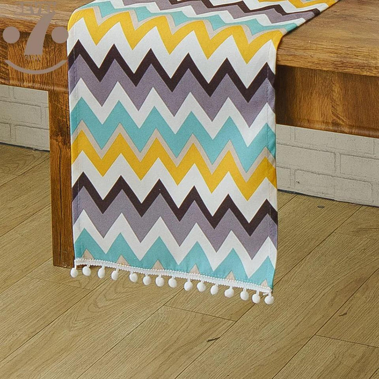 Multicoloured chevron table runner with a fringed edge.