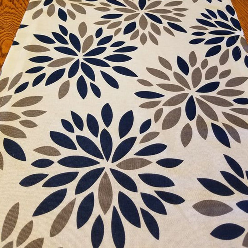 Close-up of navy and grey floral motifs on a cream table runner.
