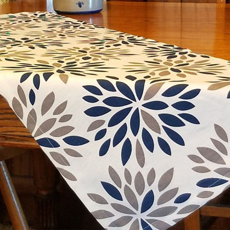 Cream table runner with navy and grey floral motifs on a wooden table.