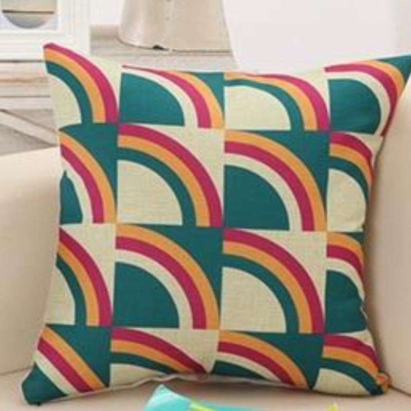 Cushion cover with repeating teal, yellow, red and navy curved geometric shapes.