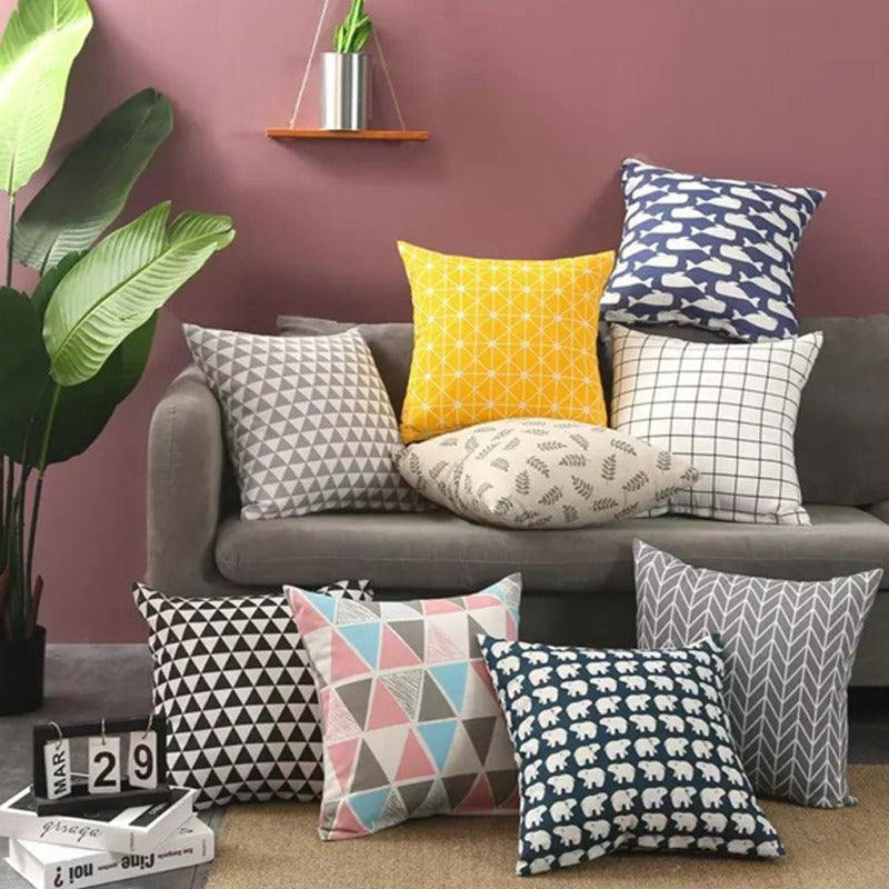 Assorted geometric cushion covers displayed on a sofa and floor.