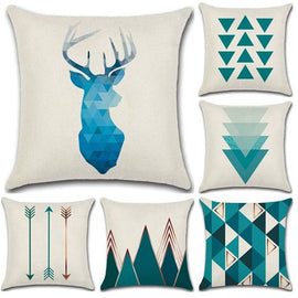 Cream cushion covers with teal deer, arrow and triangle designs.