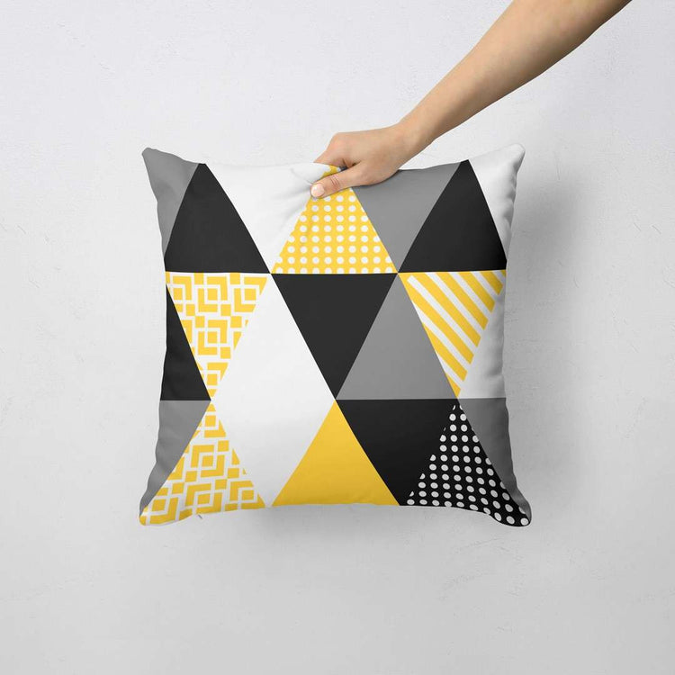 Cushion cover with large black, yellow and white patterned triangles.