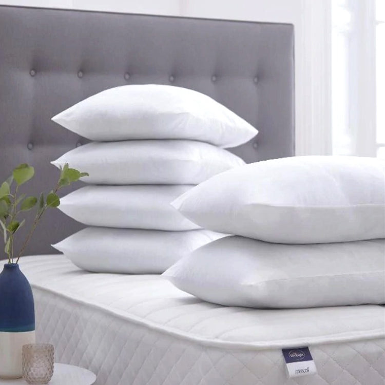 White fibre-filled pillows arranged in a group on a bed.