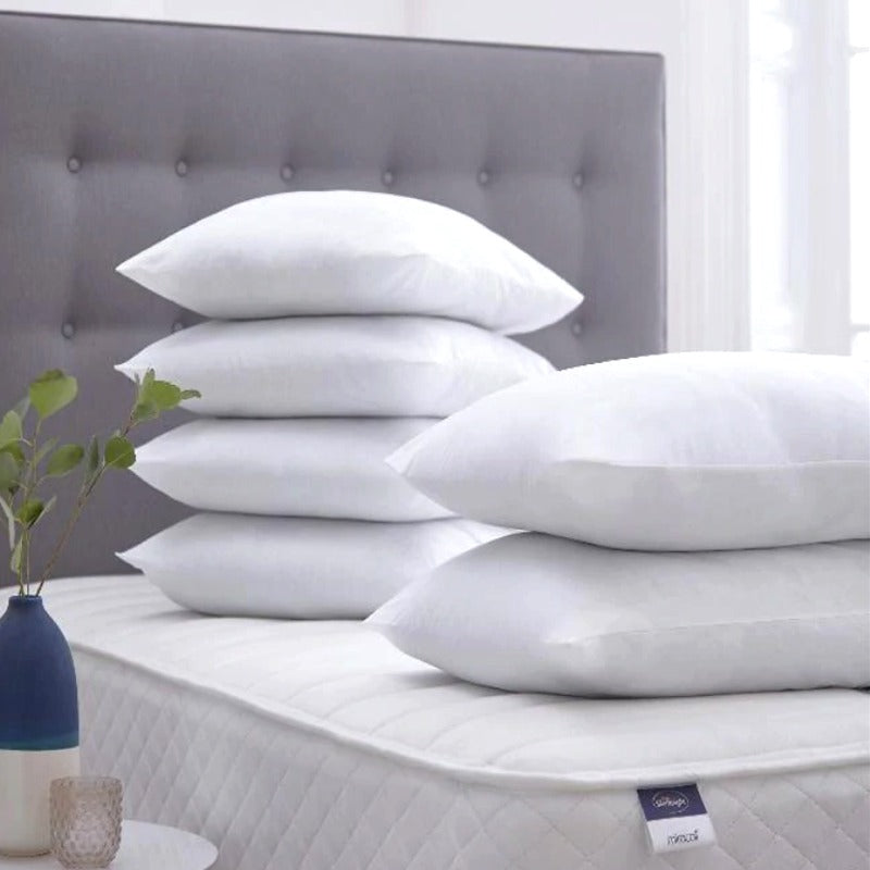 White fibre-filled pillows arranged in a group on a bed.