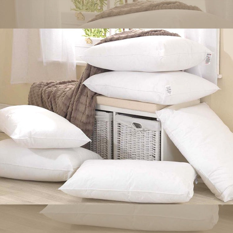 White fibre-filled pillows arranged in a group on a bed.