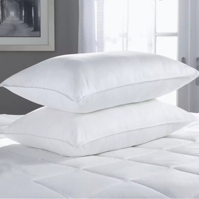 Two white fibre-filled pillows stacked on a mattress.