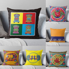 Six colourful truck art cushion covers displayed on a grey sofa.