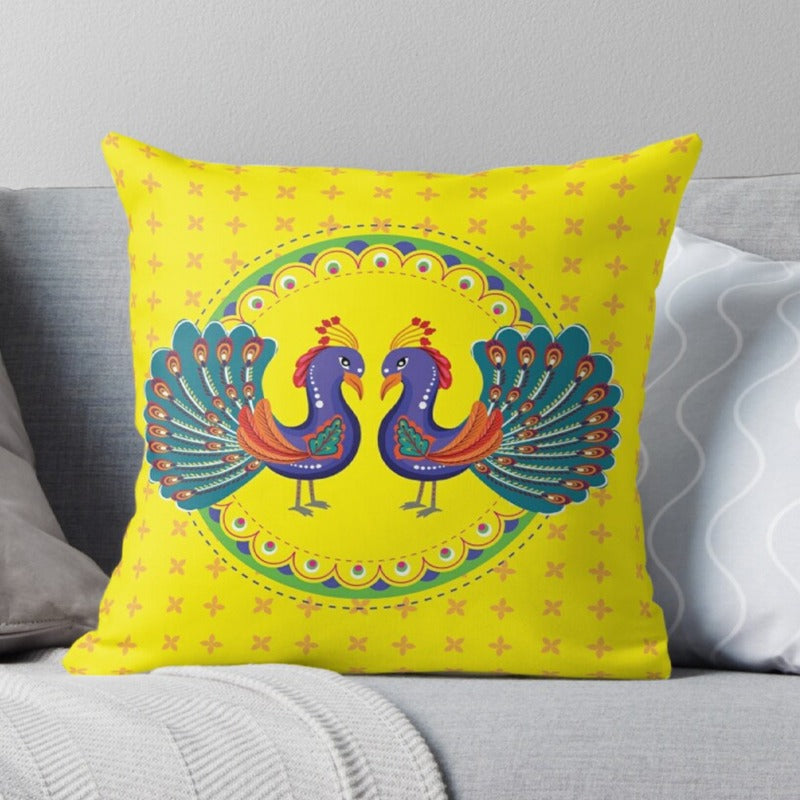 Yellow cushion cover with two colourful peacocks facing each other.