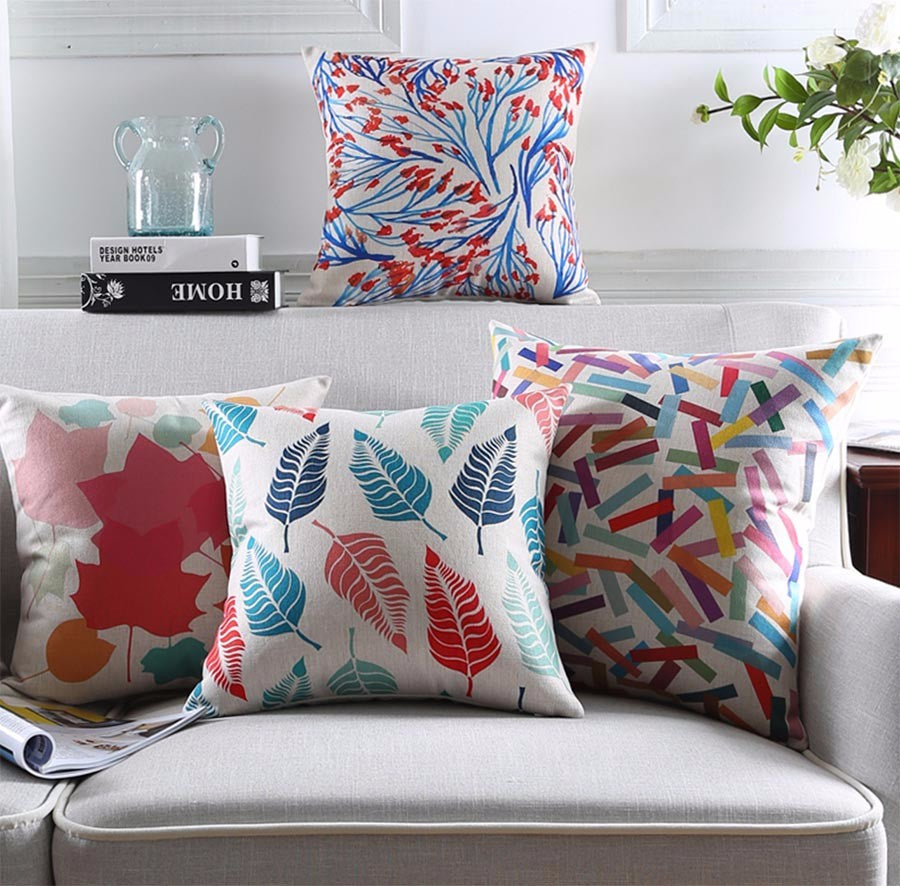 Four colourful printed cushion covers displayed on a grey sofa.