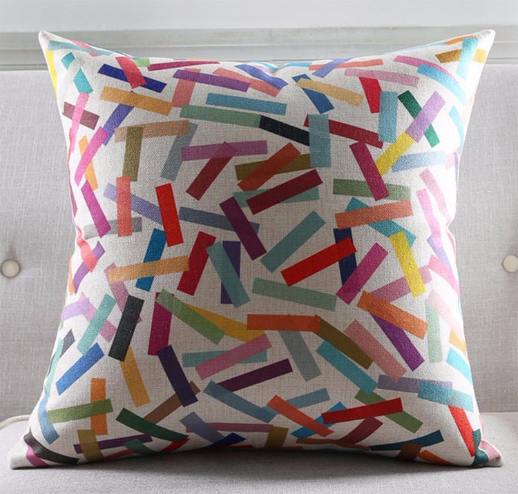 White cushion cover with scattered multicoloured rectangular strokes.