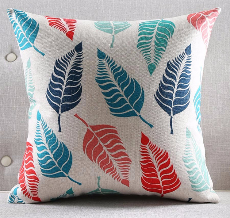 White cushion cover with large teal, blue and red leaf prints.