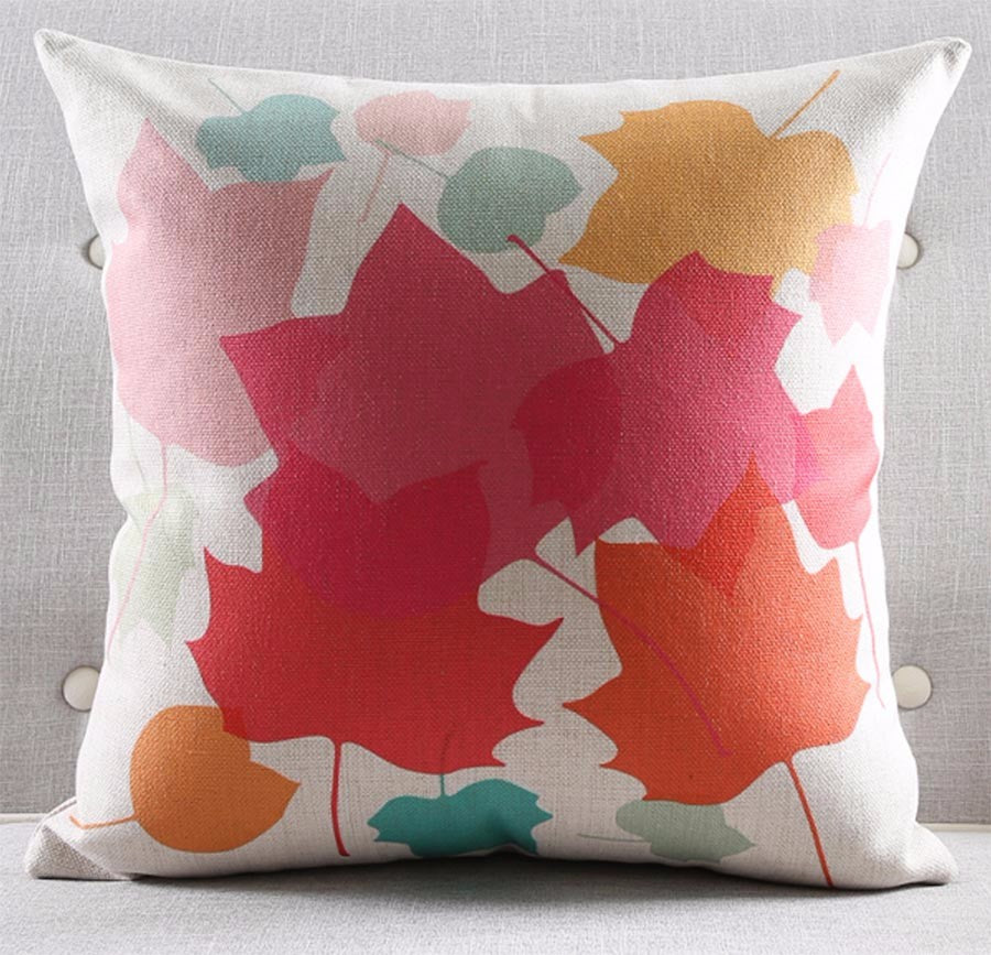 White cushion cover with large overlapping pink, red, orange and green abstract shapes.